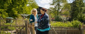 Haus Eckberg Zwei Frauen betreten den Garten durch das Gartentor.