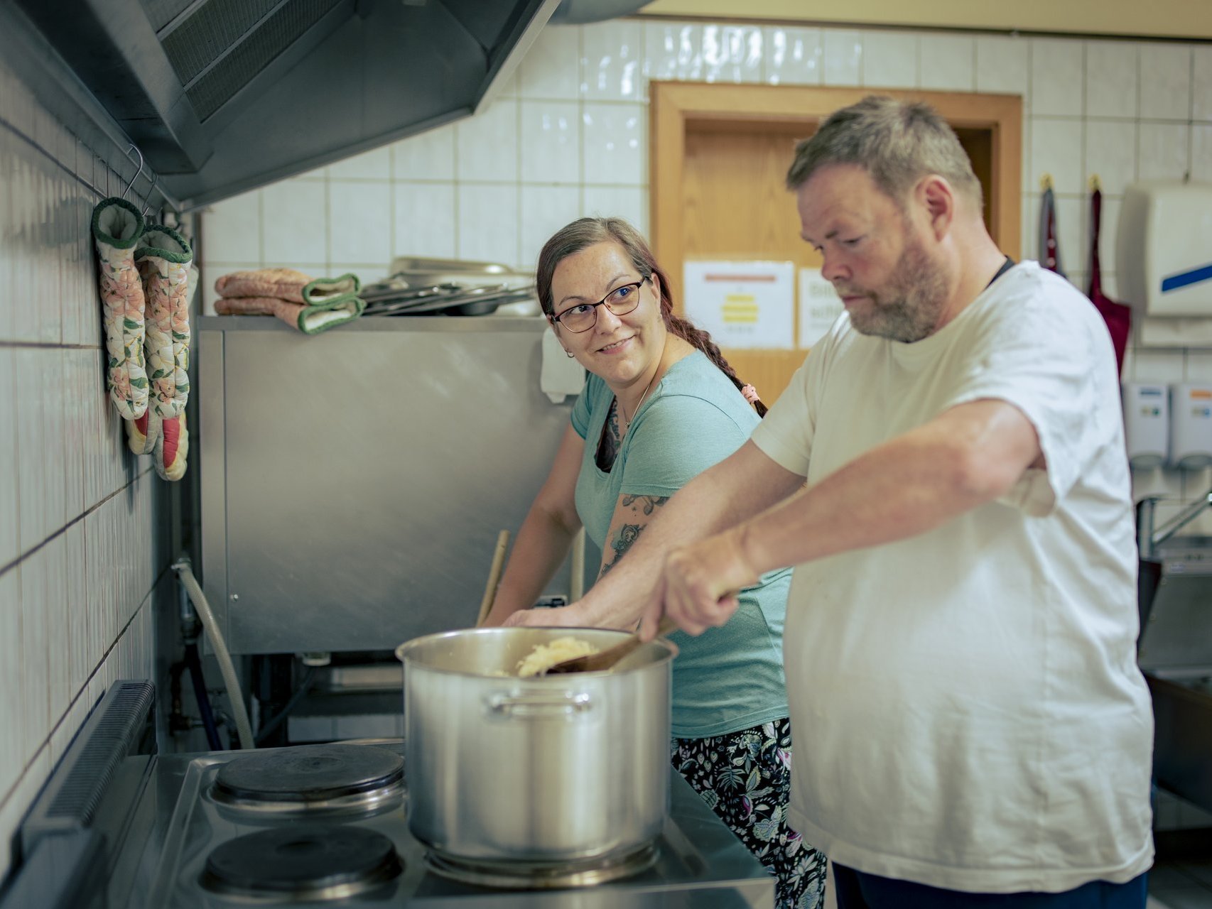 Eine arbeitsanleiterin kocht in einer küche mit dem suchtkranken menschen