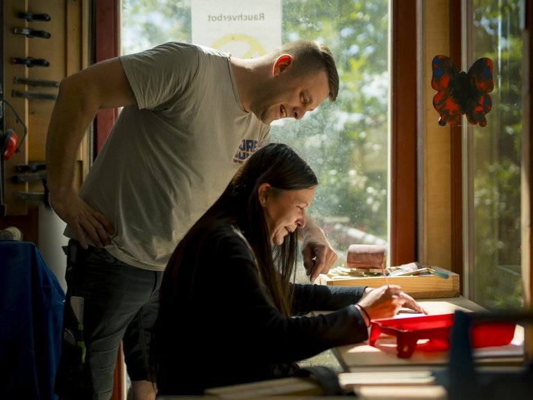 Ein Mann und eine Frau sitzen an einem Schreibtisch und tauschen sich aus.