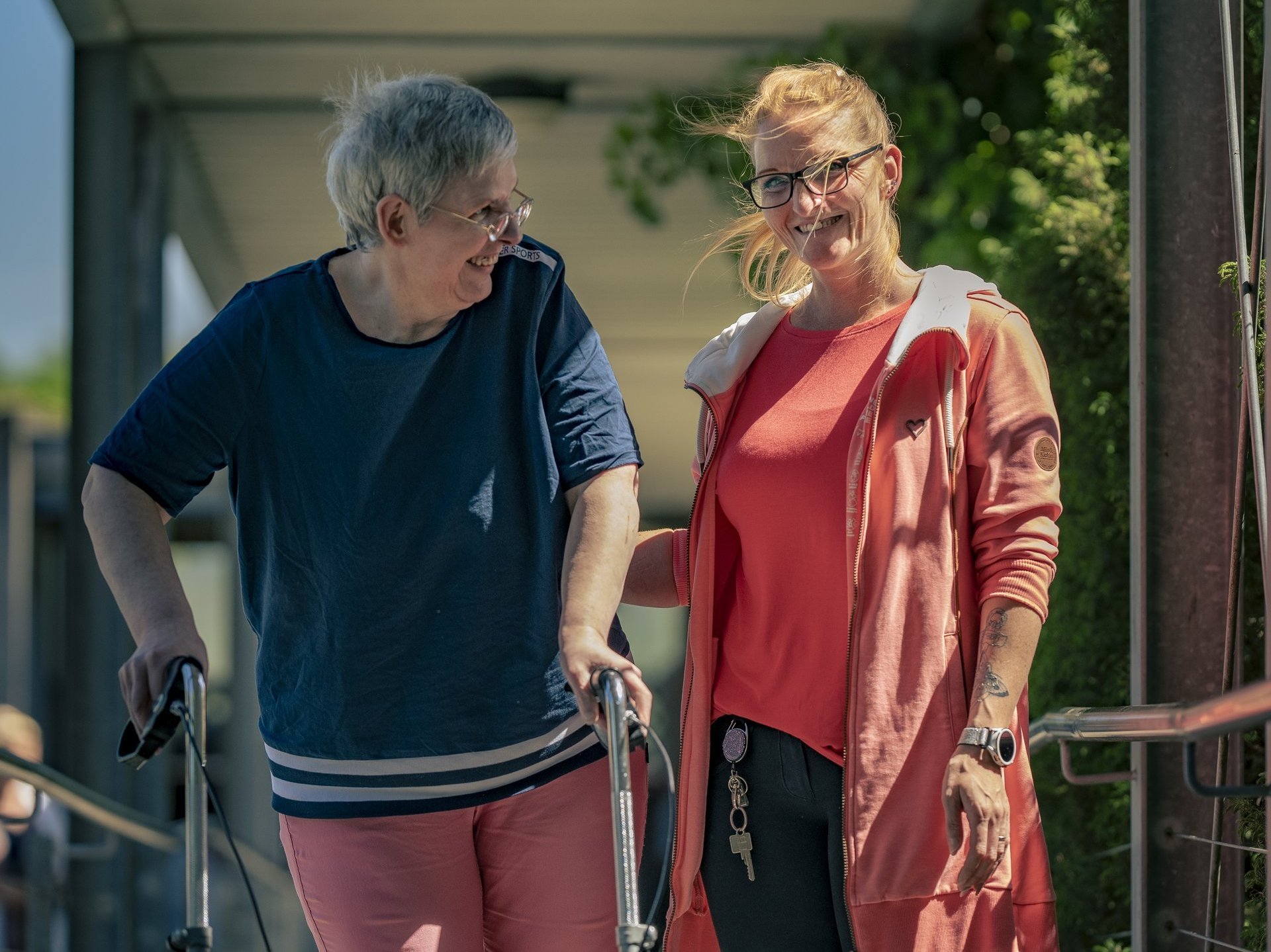 spaziergang einer bewohnerin in begleitung einer betreuerin beide strahlen freudig