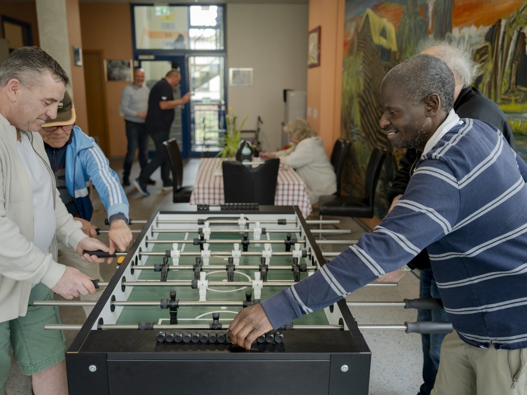 Mehrere Personen spielen am Fussballkicker und haben Spass.