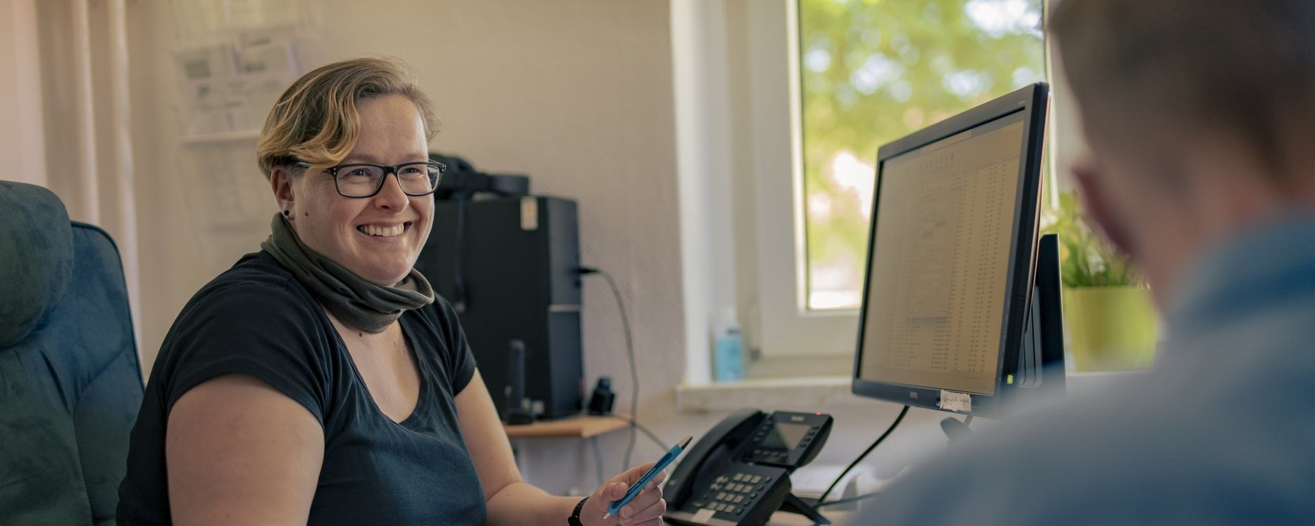 Zwei Person sitzen vor einem PC und unterhalten sich. 