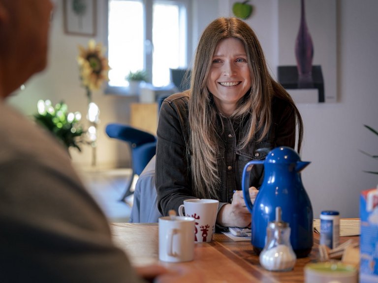 Zwei Personen sitzen an einem Tisch und trinken Kaffee oder Tee.